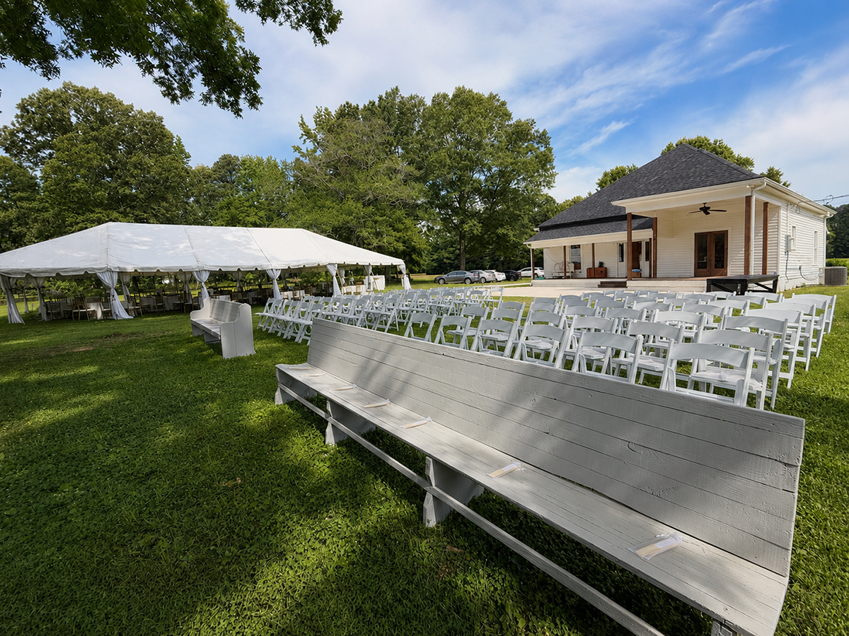 White church style benches, chairs, outside seating, and a glimpse of the outside of the venue.