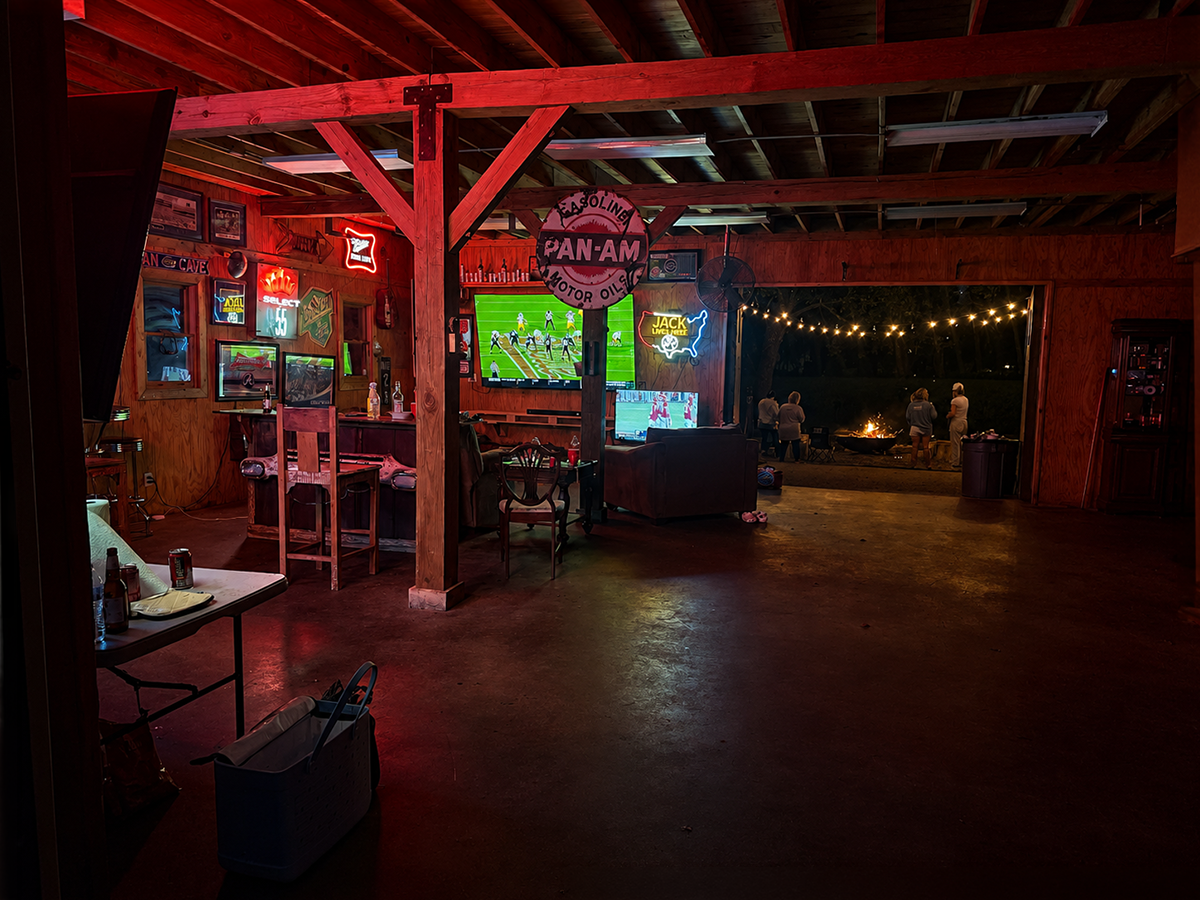 A mancave and entertainment area at night with red lighting and an outdoor firepit.
